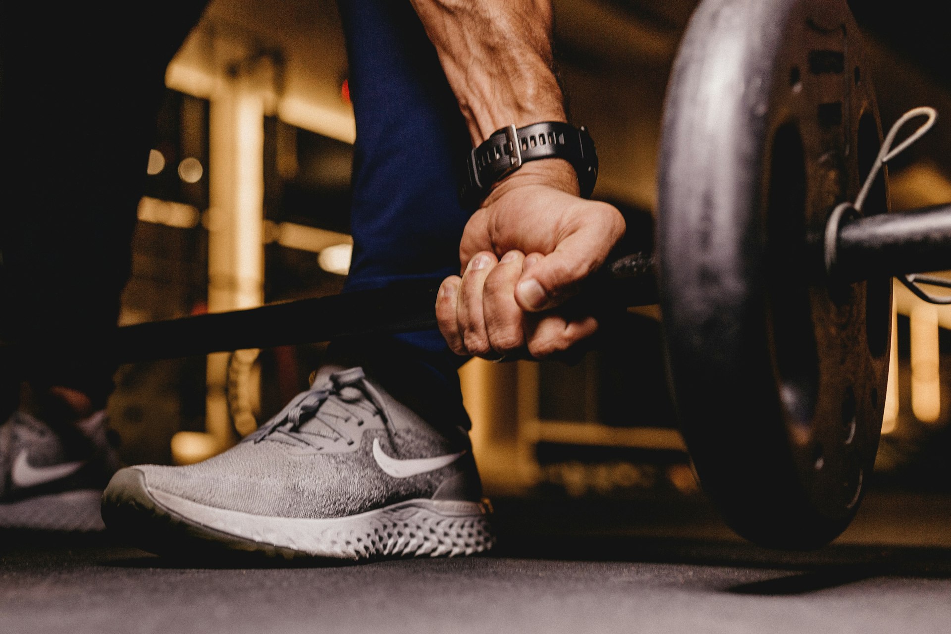 A hand gripping a loaded barbell on a gym floor
