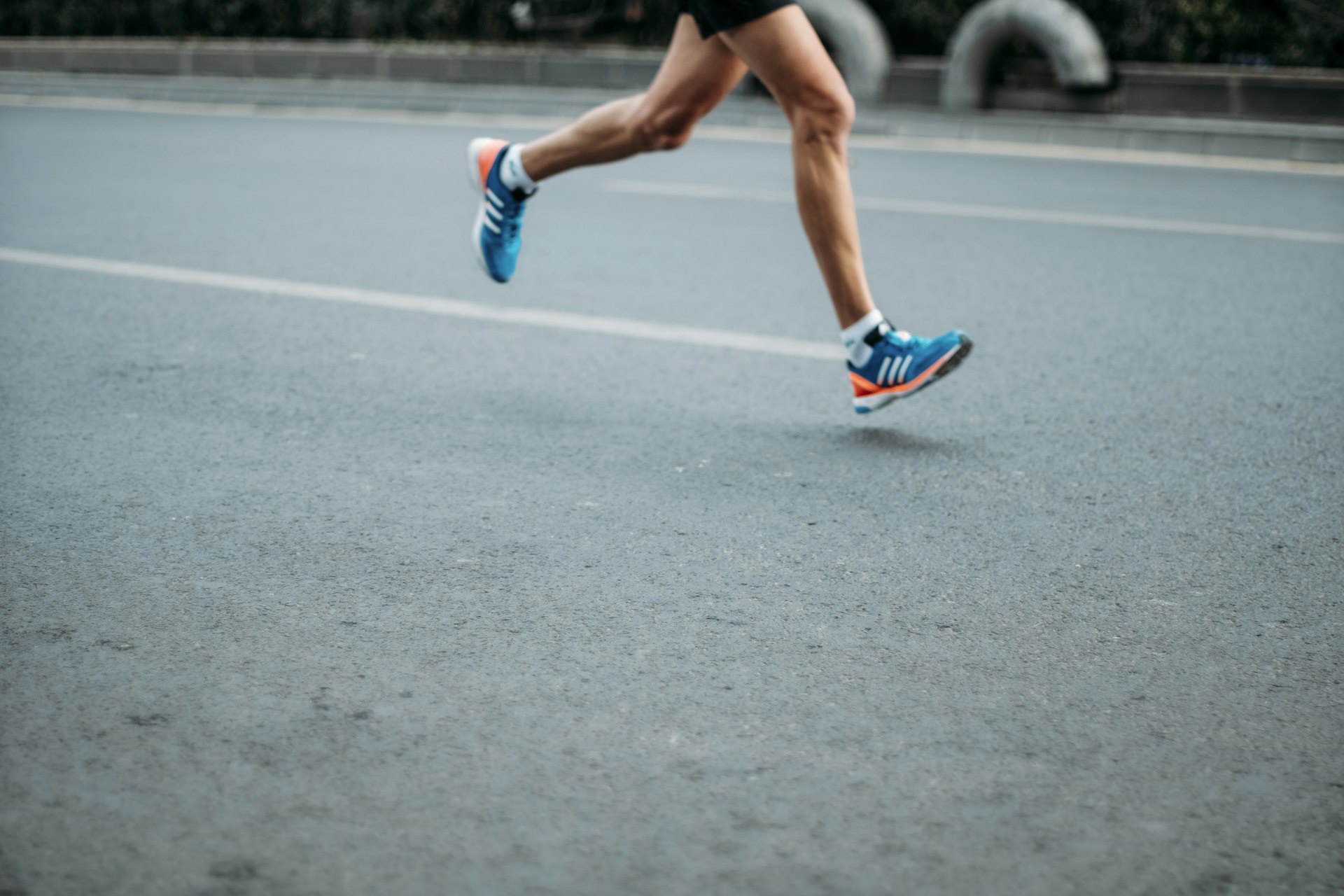 A runner mid-stride on a road, seen from the knees down